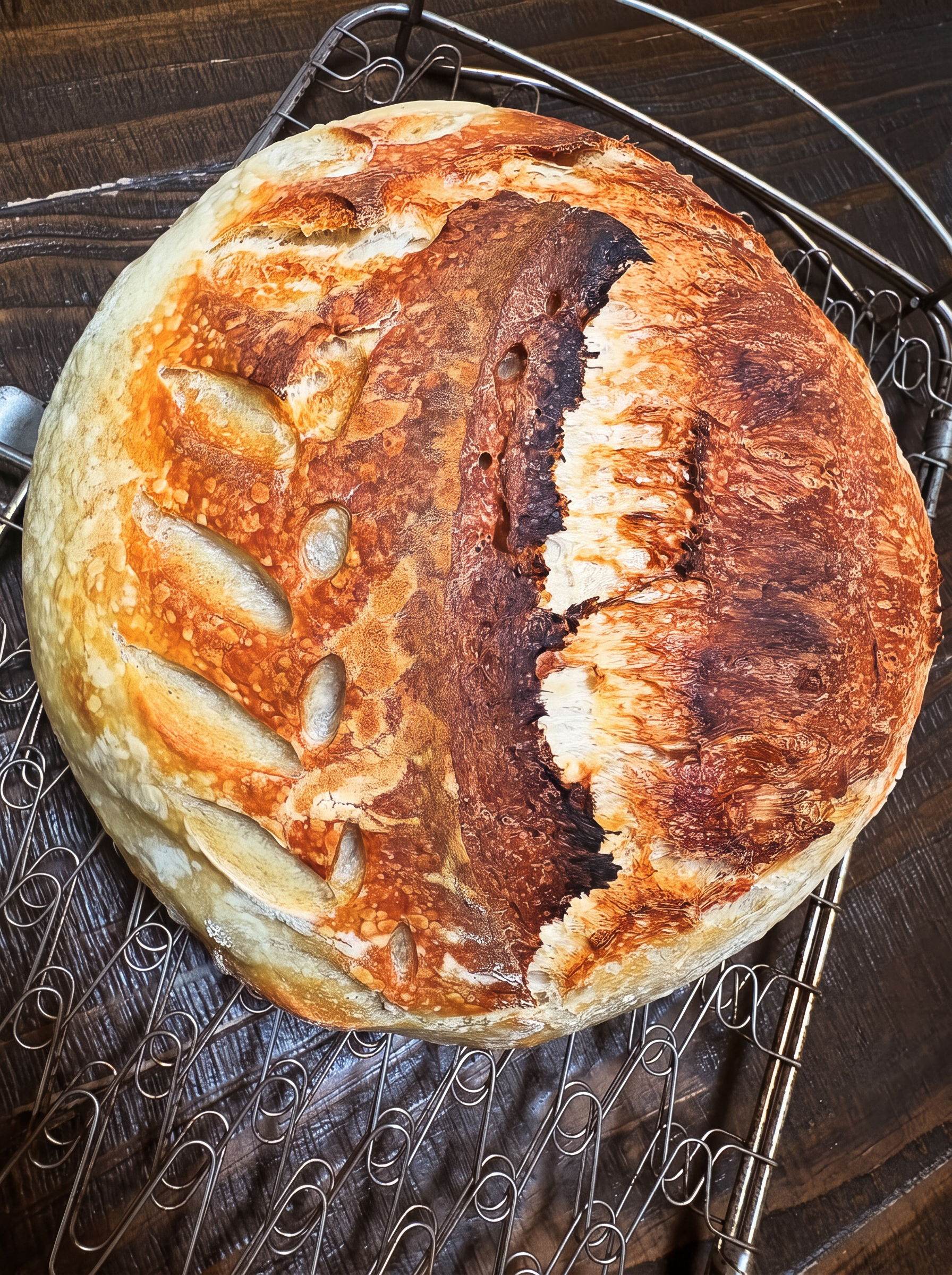 Scored artisan sourdough loaf with a deep golden crust on a cooling rack
